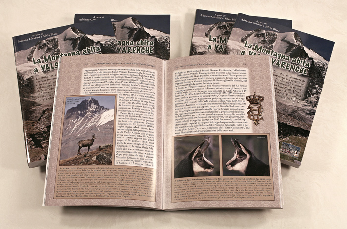 foto con alcune copie del libro La Montagna abita a Valsavarenche, in primo piano il libro aperto su due pagine del secondo capitolo con foto di camosci