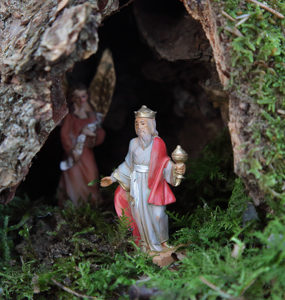statuetta re magio in una capanna di corteccia con dietro angelo